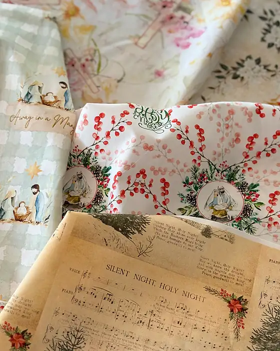 A stack of Holy Homes Christmas fabrics, including Away in a Manger, O Holy Night and Silent Night